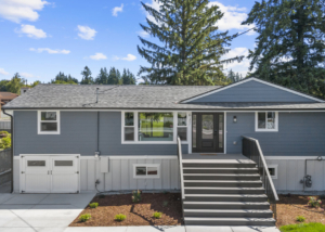 Blue, single-story ranch-style home with a raised entry accessed by wide gray stairs and a black front door, white trim, and a split-level foundation.