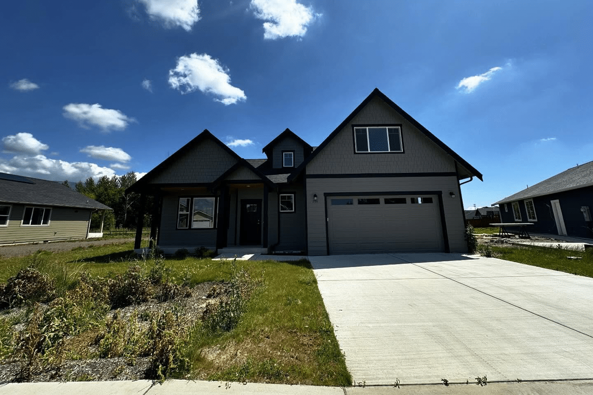 home-service-residential | Laika Construction | Bellingham Contractor Front view of a gray modern house with a two-car garage and a concrete driveway under a bright blue sky