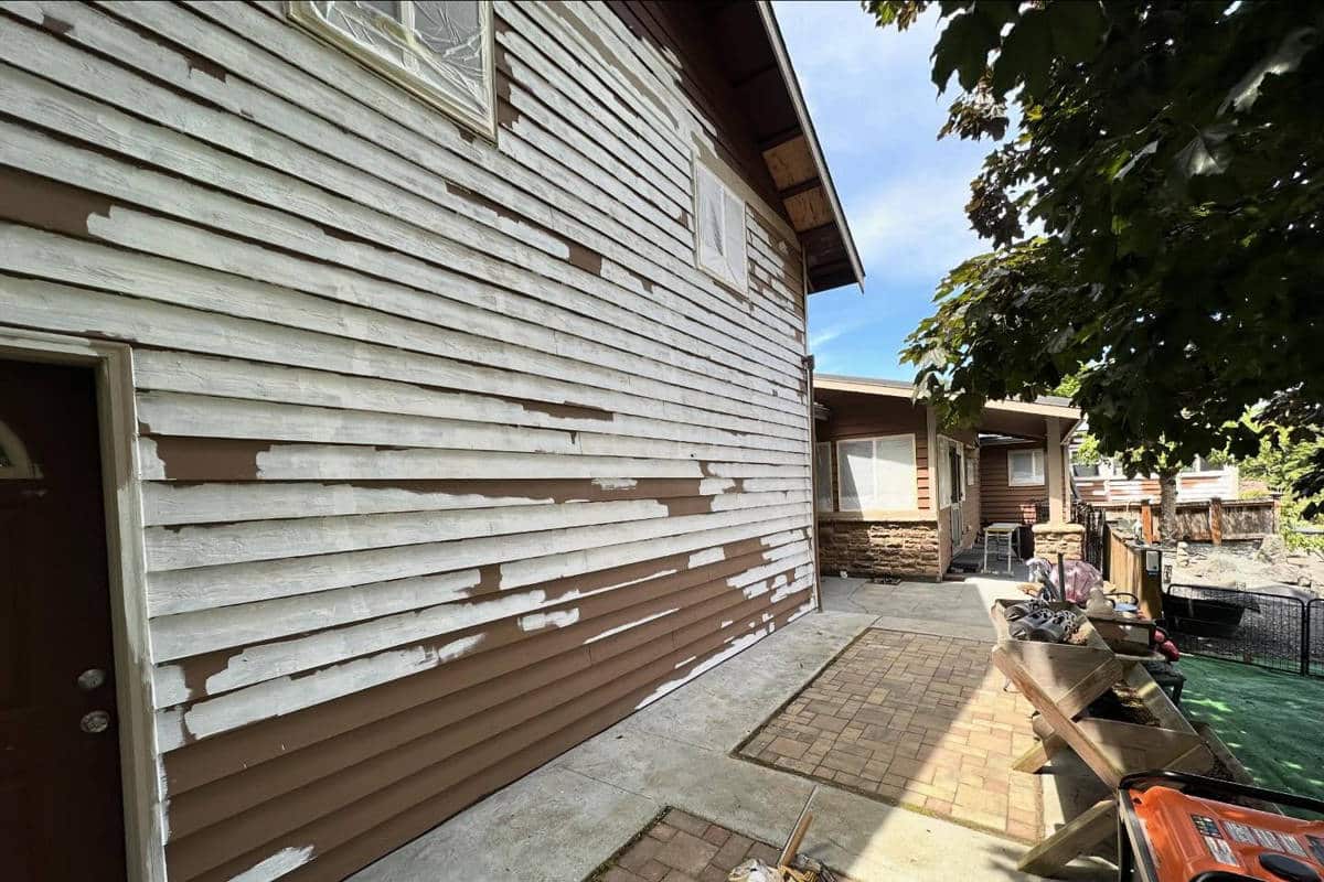 The side of a home partially covered with primer as part of an exterior painting project with Laika Construction.