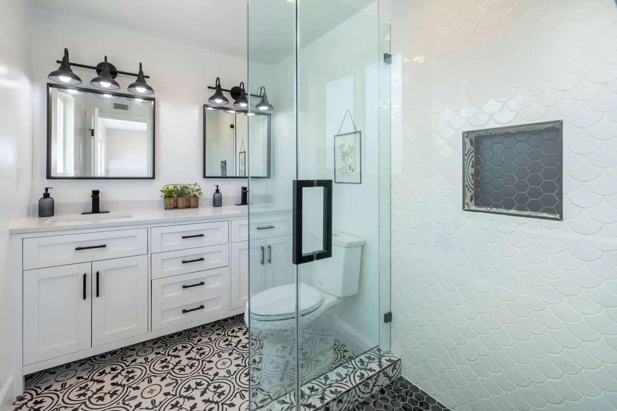 A stunning bathroom with a walk-in shower, white cabinets, new fixtures and tiles after getting a bathroom remodel from Laika Construction.